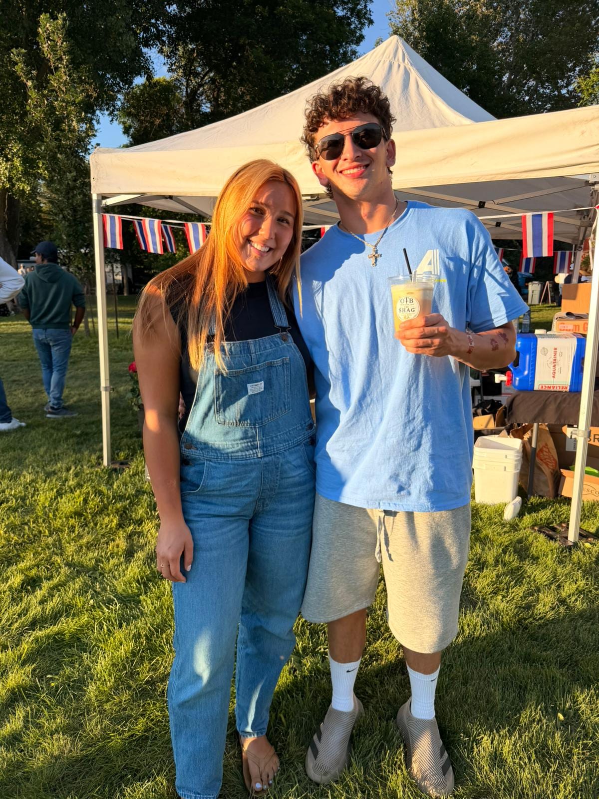 A smiling couple holding an OTB Shag lemonade in the park