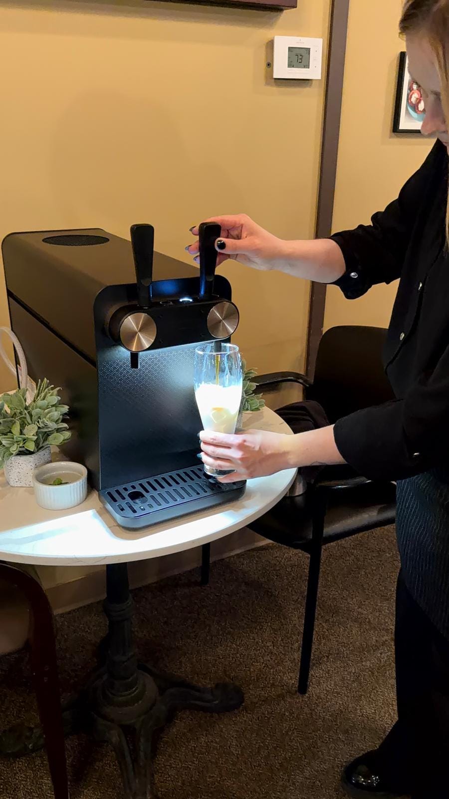 A creamy beverage being poured fresh from the nitro tap into a glass